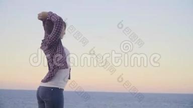 年轻女子<strong>站在山顶</strong>，望着大海。 日落。 希腊。 克里特岛。